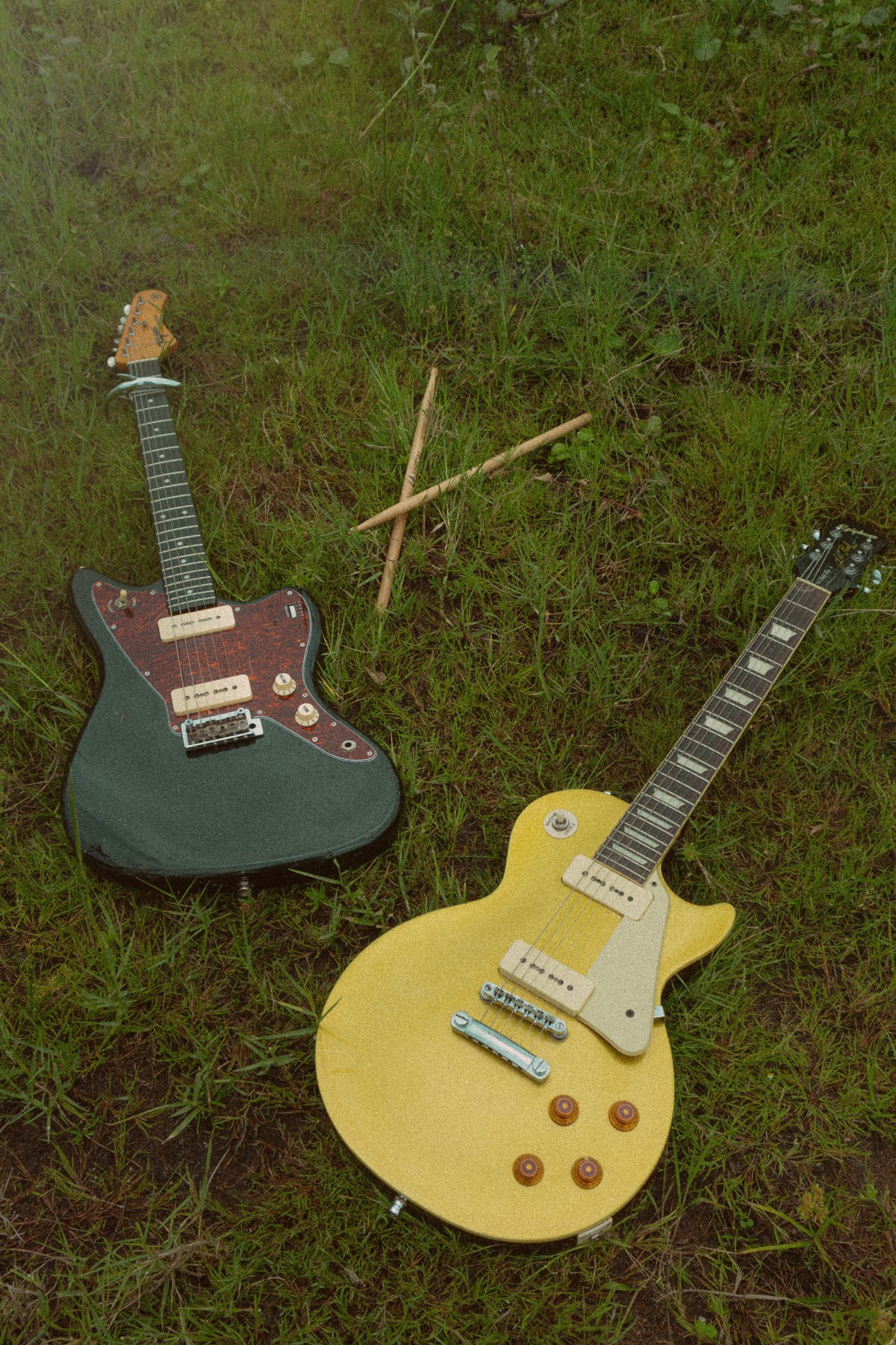 Duas guitarras e baquetas largadas na grama